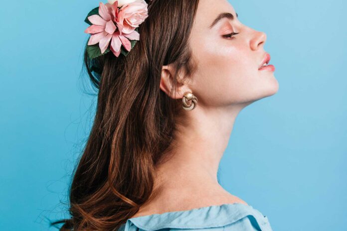 Djevojka na plavoj pozadini sa cvjetnim vijencem na glavi