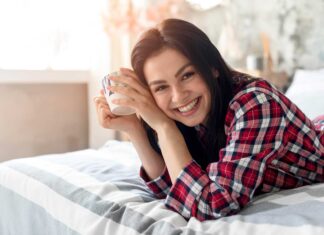 Brineta se smiješi sa šalicom kave ujutro u krevetu.