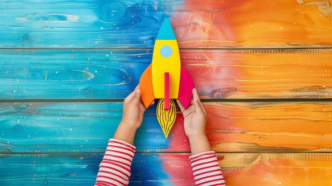 young-girls-hands-holding-colorful-wooden-rocket-anticipation-(1) djecja ruka drzi napravljenu raketu