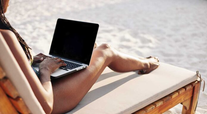 žena na plaži radi na laptopu