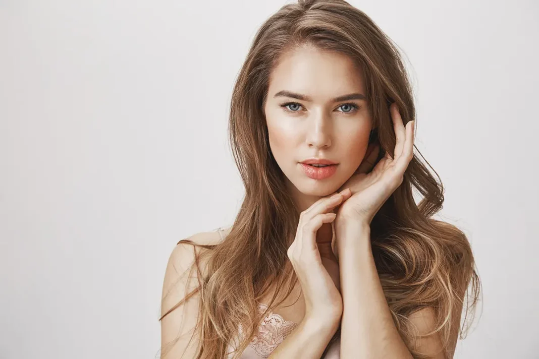 glamour-feminine-woman-touching-face-looking-camera Model gleda u kameru držećo ruku na licu