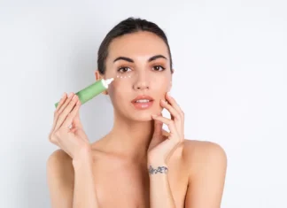 Djevojka stavlja kremu na podrucje oko ociju.