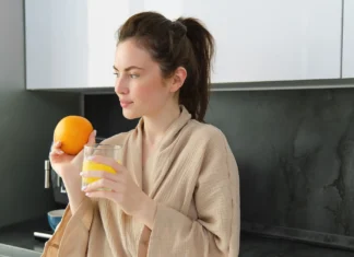 Djevojka s narančom i čašom vode u kuhinji