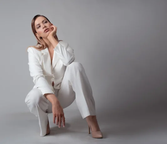 mlada žena u bijelom odijelu i štiklama, studio portret