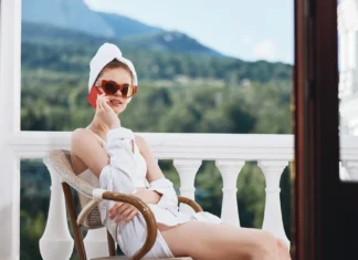 Djevojka sjedi u ogrtacu sa suncanim naocalama na balkonu